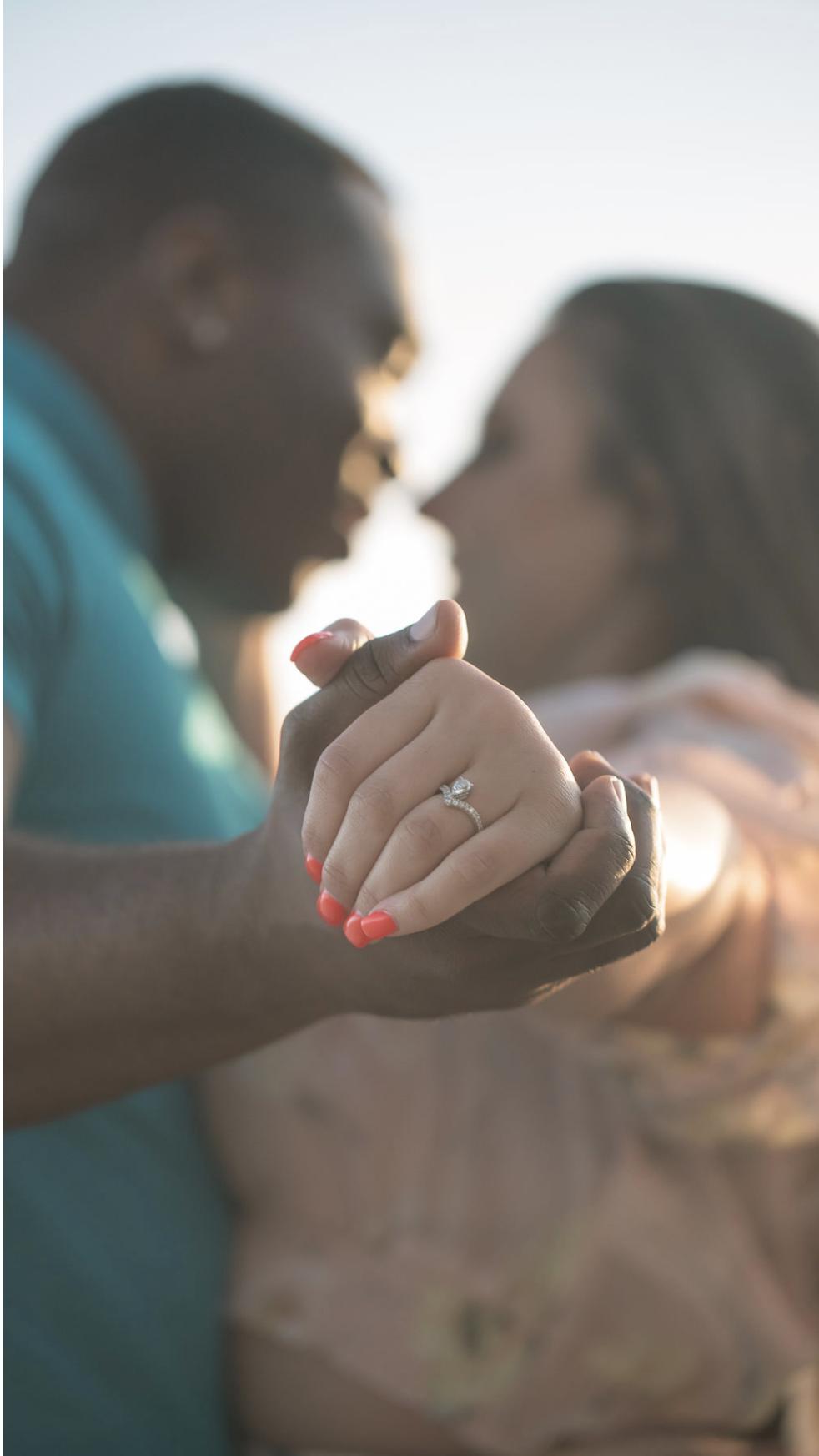 A couple holding hands with an engagement ring in focus