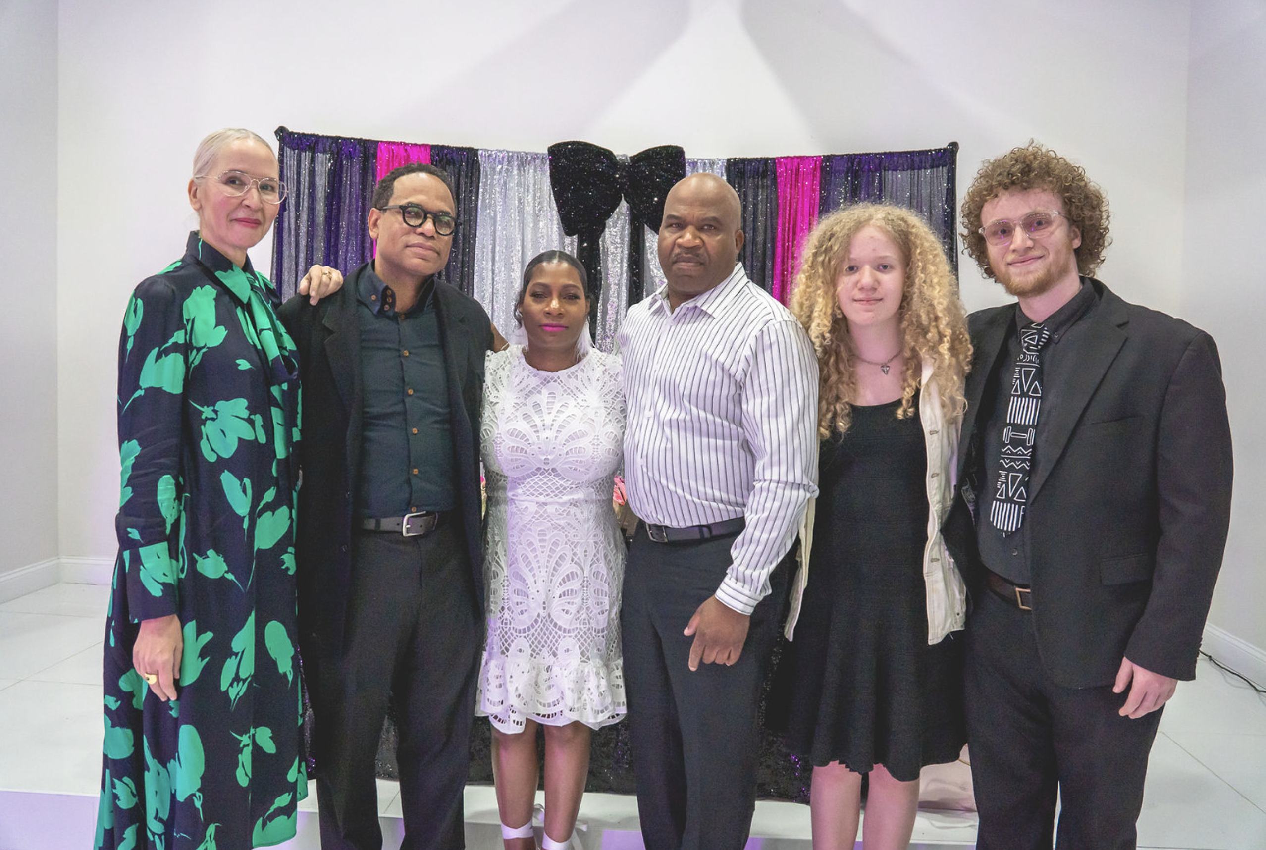 Six guests posing together in front of a festive backdrop