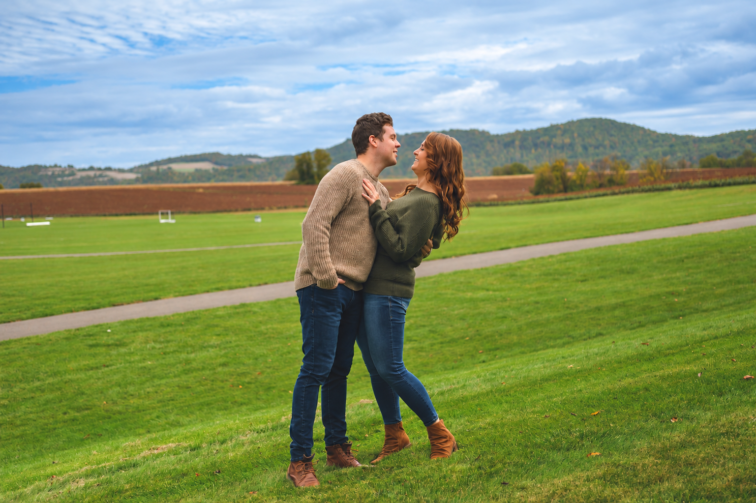 A couple sharing a joyful embrace in an open green field