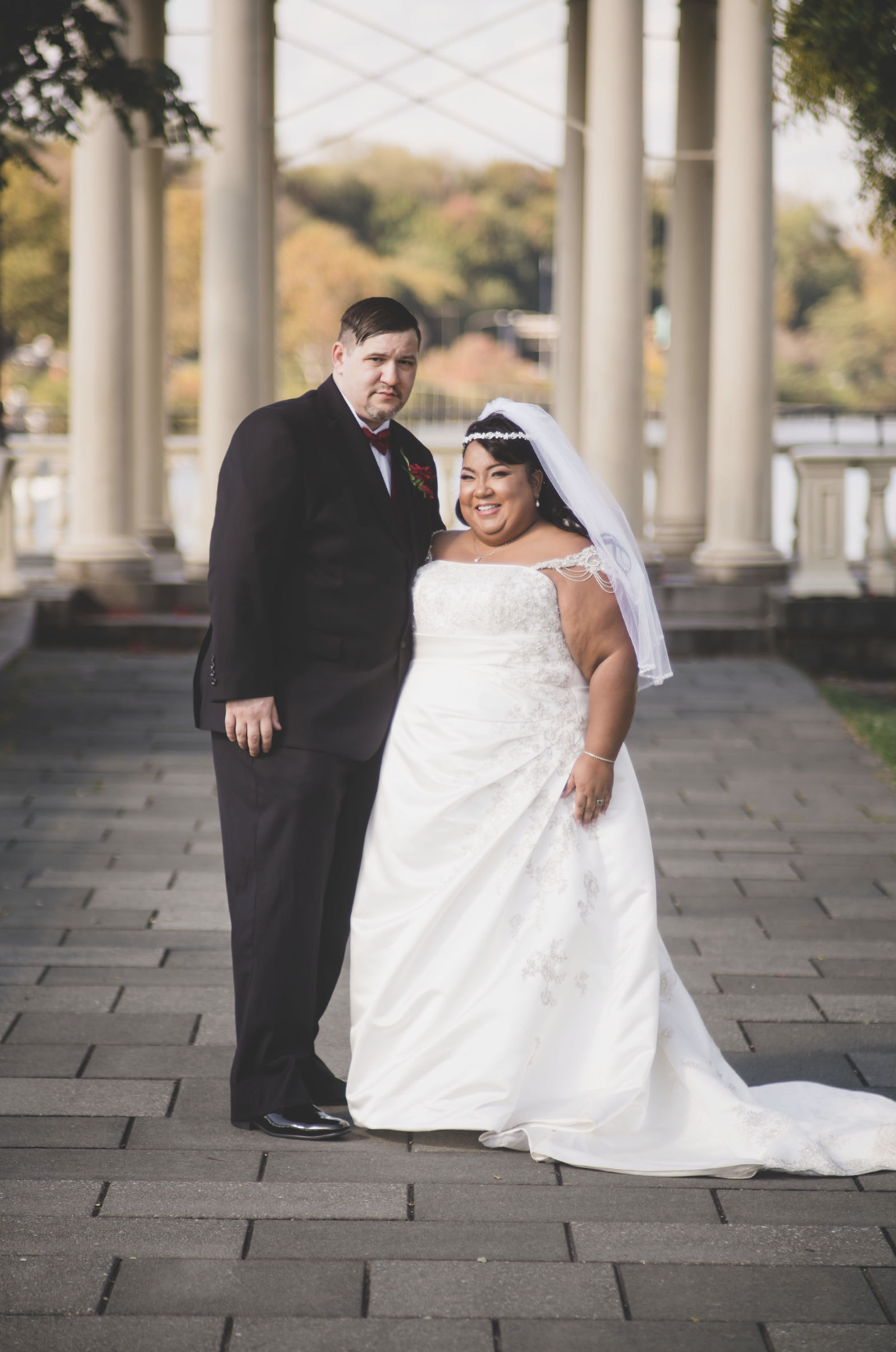 A wedding couple standing together beneath garden columns